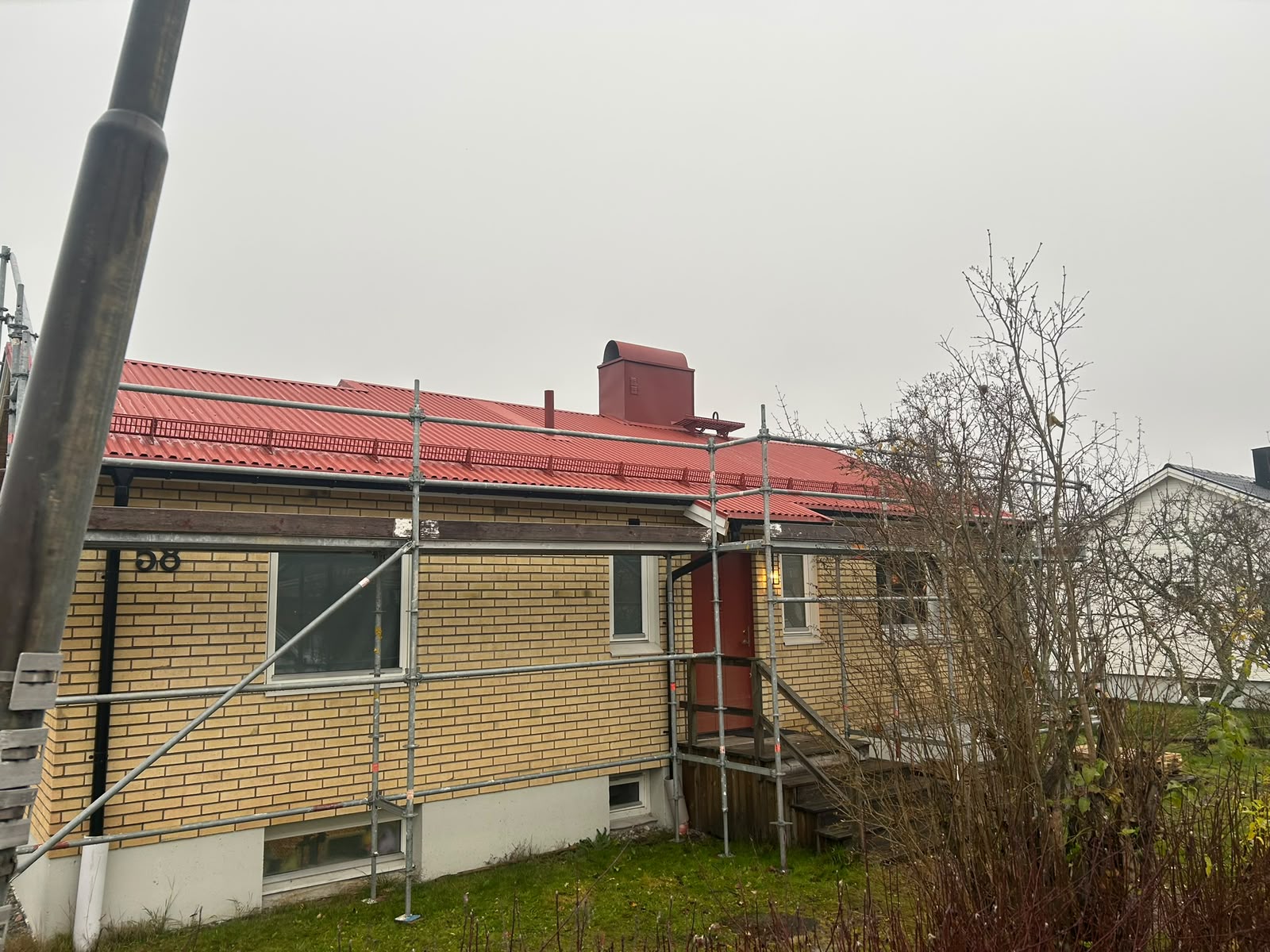 Rött plåttak och skorsten på tegelhus