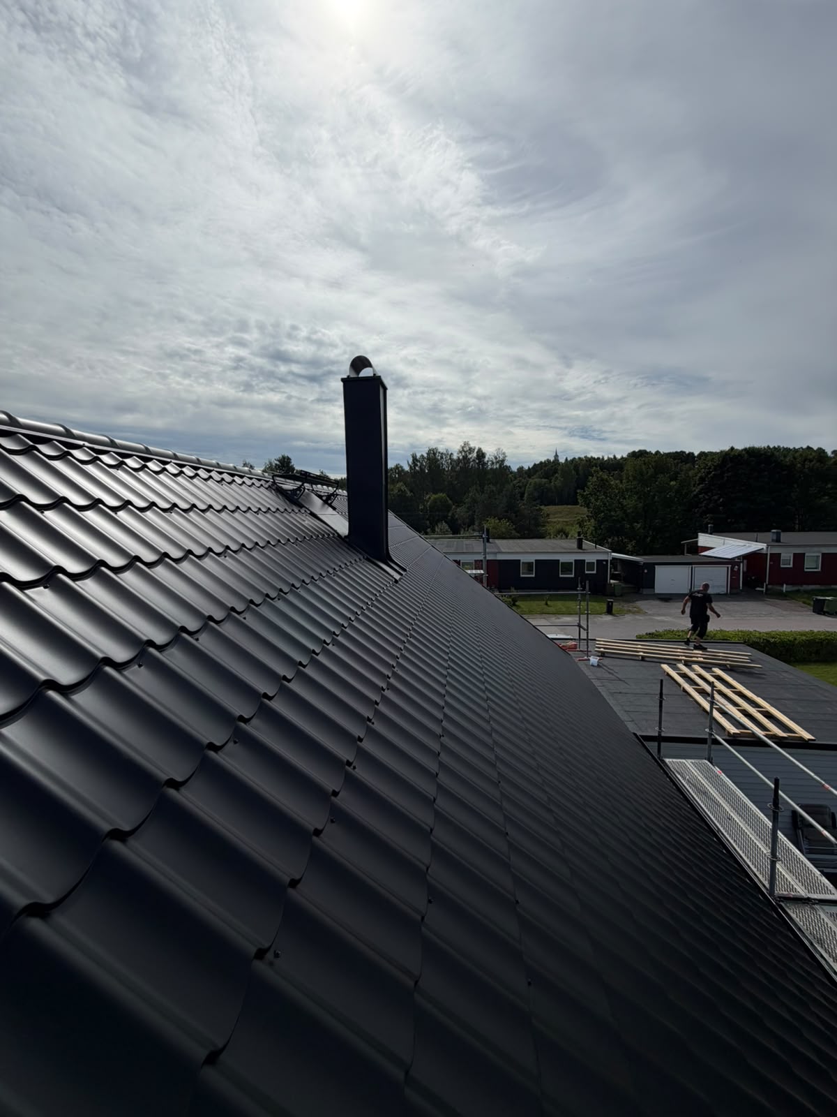 Nytt mörkt plåttak med plåtinklädd skorsten
